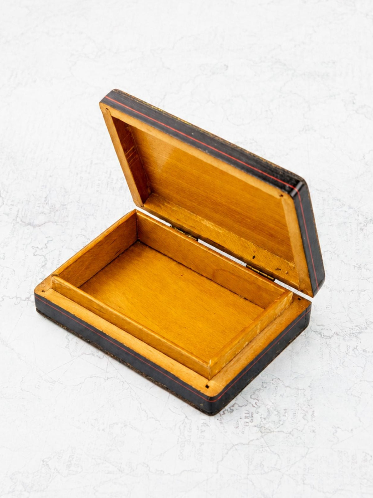 An open rectangular wooden keepsake box with a glossy warm honey-amber interior and dark brown outer edges, photographed on a light textured white background.