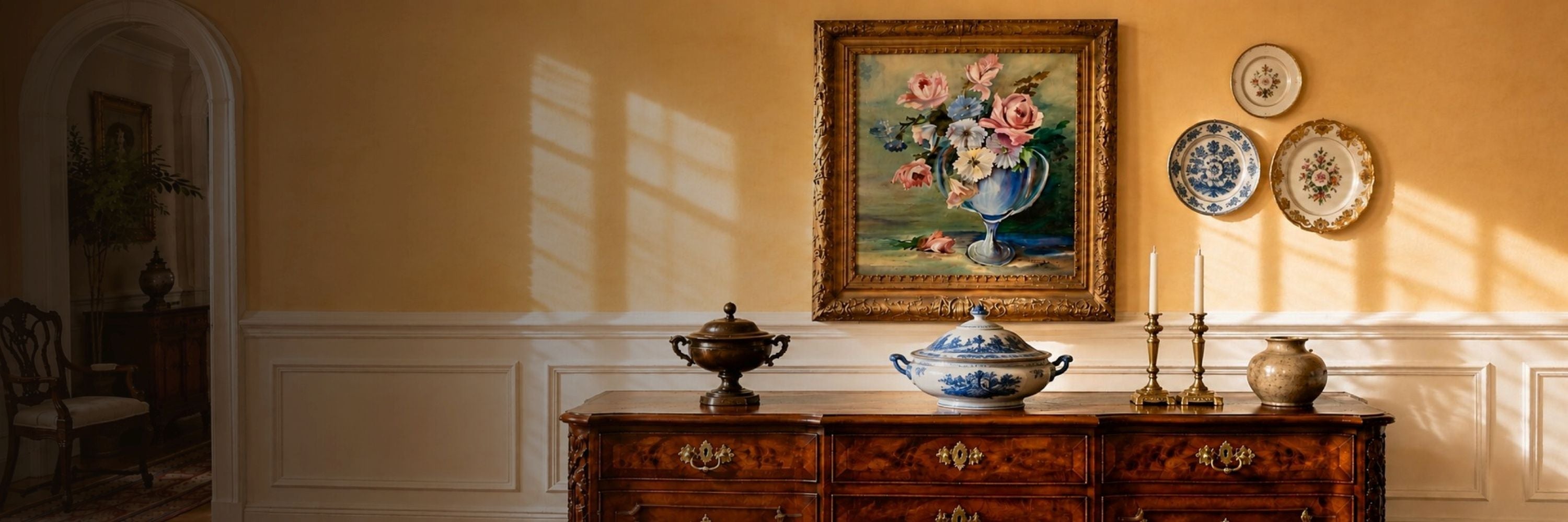 Décor collection featuring antique artwork, decorative glass, ceramics, and brass accents displayed on an elegant wooden console