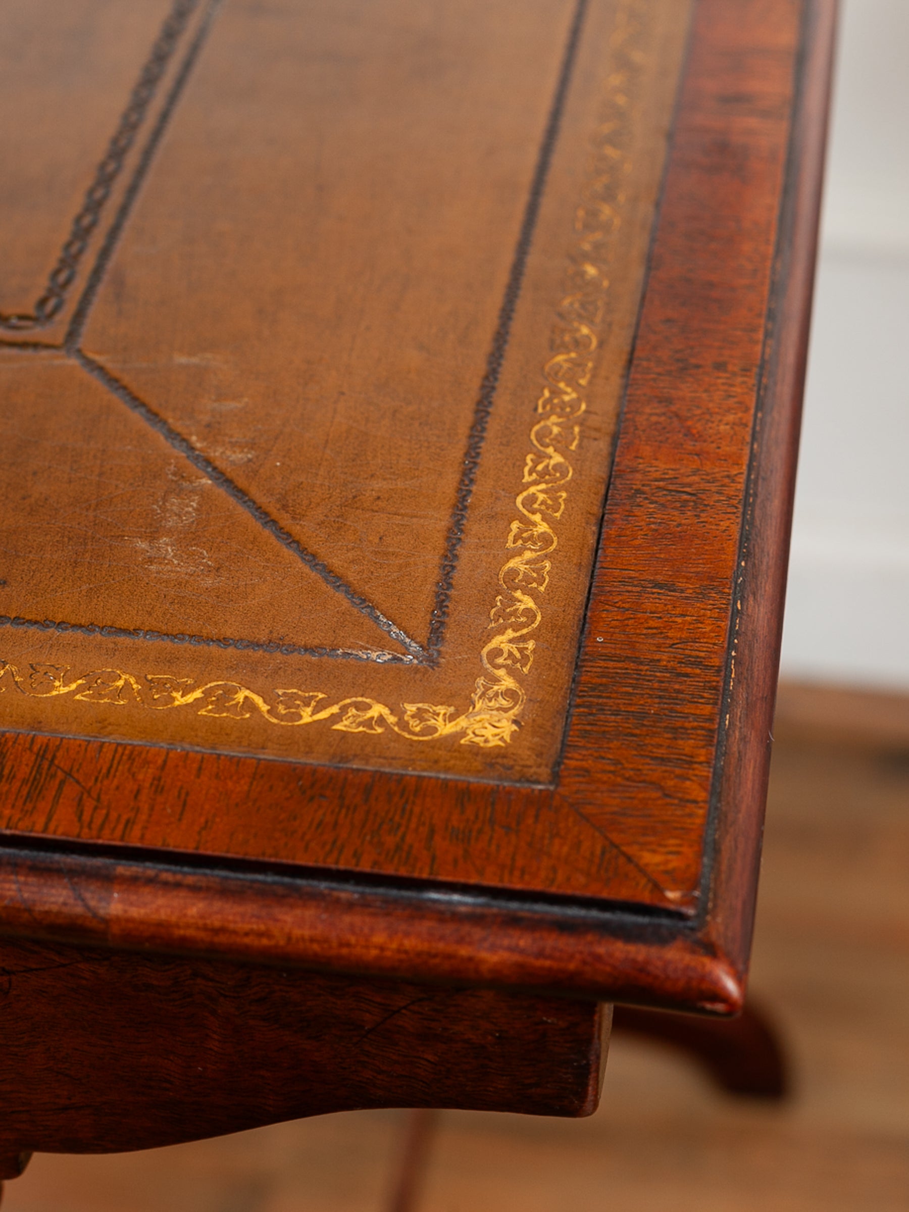 Close-up of a polished dark brown wooden table corner showing decorative gold and black inlay on the tabletop surface.