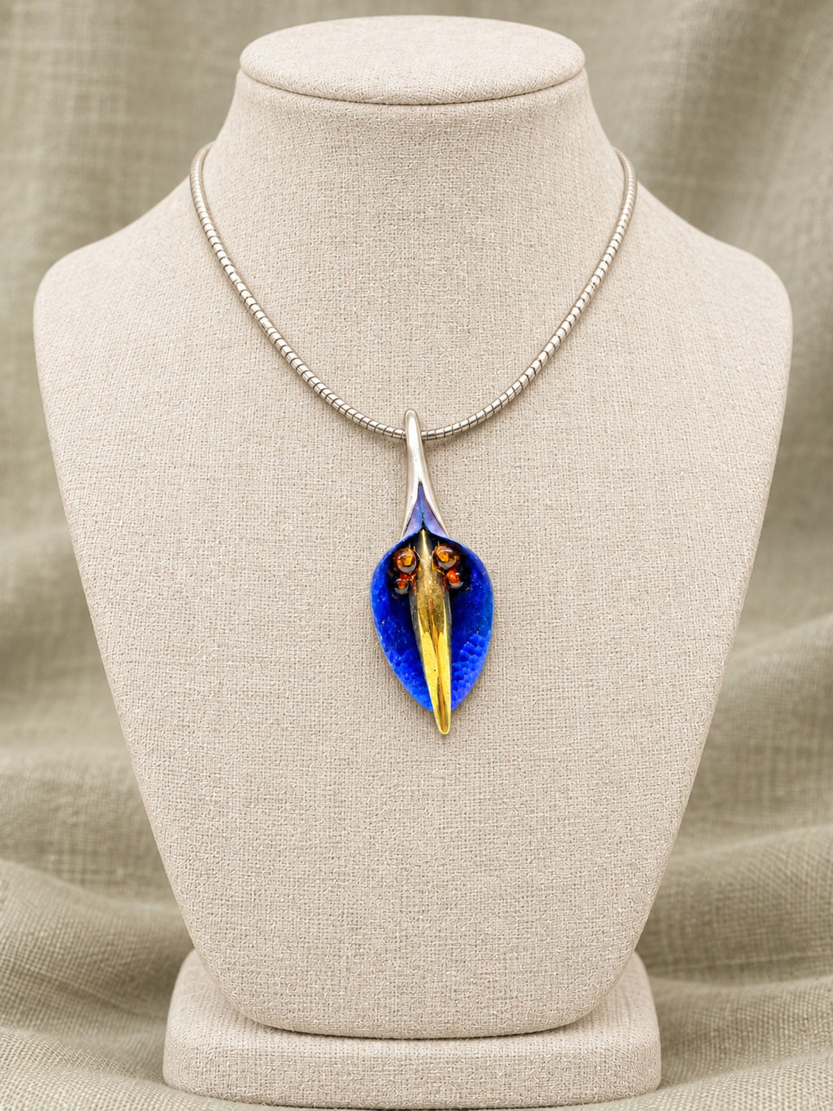 Baltic Amber, Titanium & Sterling Silver Flower Pendant with Cognac Amber Spheres, displayed on a beige fabric-covered jewelry bust against a neutral draped background.