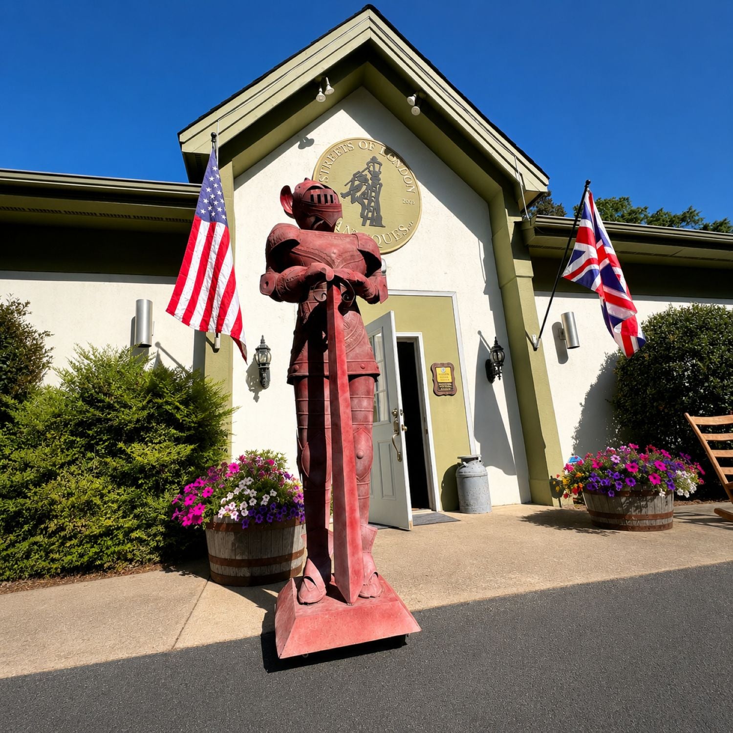 Statue of a knight in armor outside a building with American and British flags.