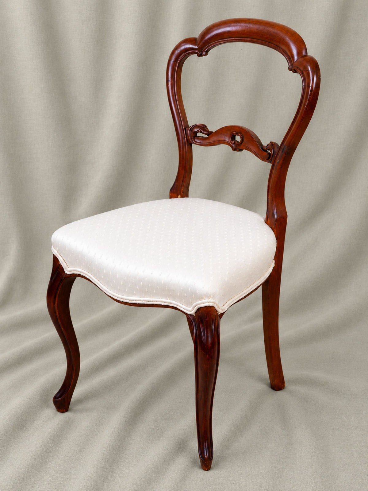 beautiful Mahogany balloon back chair with a light upholstered seat again linen backdrop.
